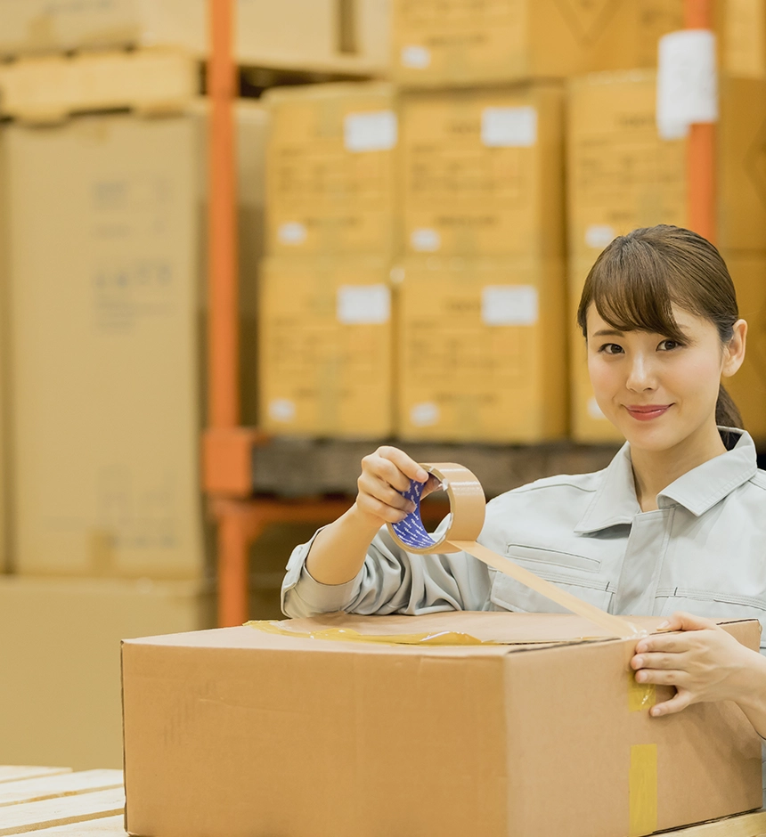 Logistics worker packaging a box in a warehouse.